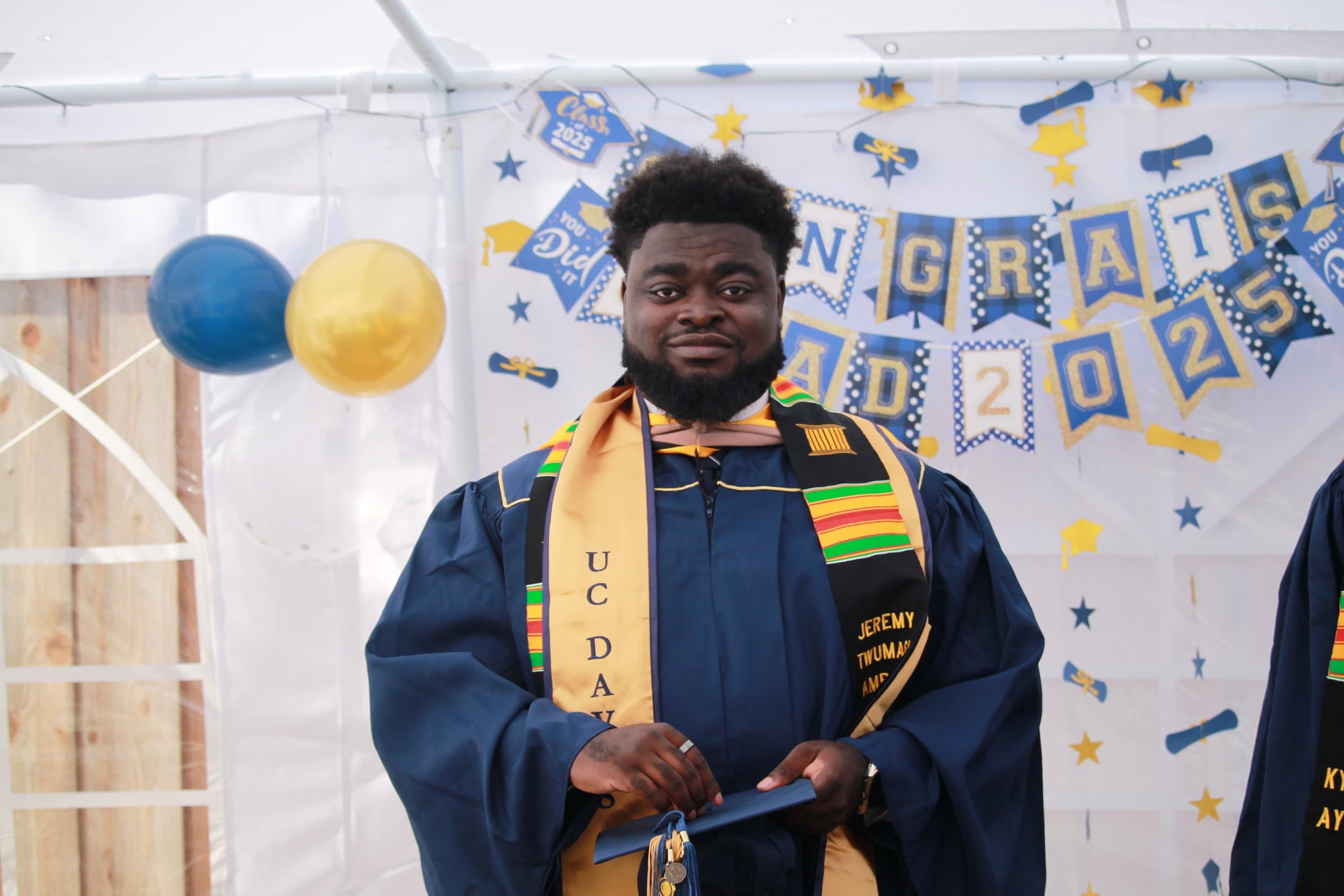 Jeremy Ampofo in a UC Davis graduation gown with a kente cloth stole